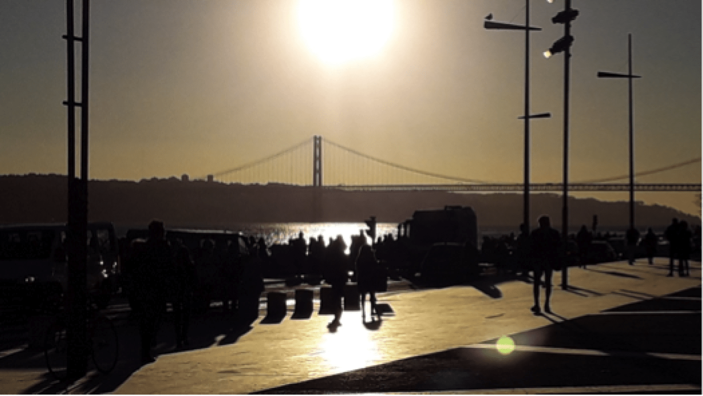 Lisbon riverside with sun above bridge