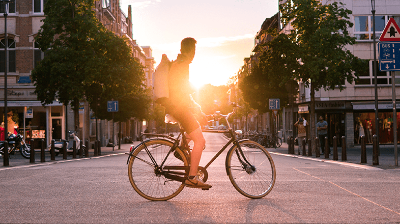 person on bike in the middle of a road in front of sunshine