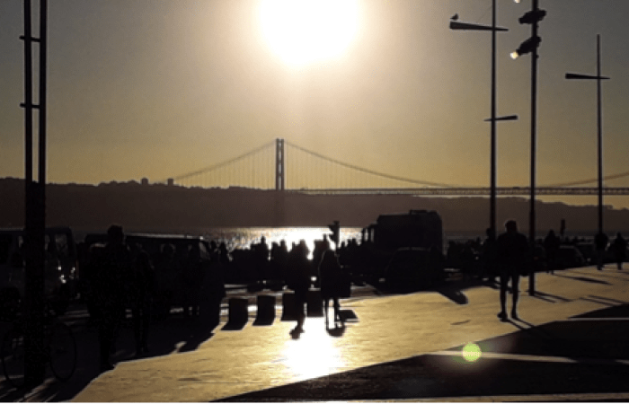 Lisbon riverside with sun above bridge