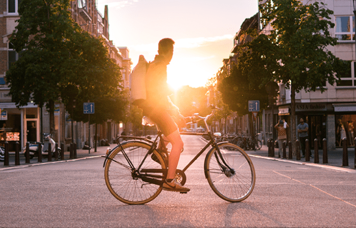person on bike in the middle of a road in front of sunshine